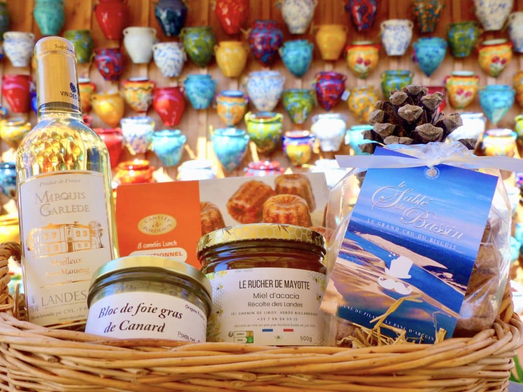 Sélection de produits régionaux : bouteille de vin blanc, cong-fiture, foie gras des Landes dans un panier en osier